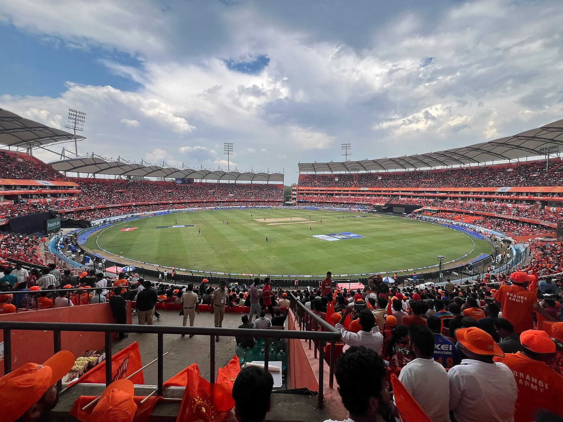 Packed stands at the Rajiv Gandhi International Stadium in Hyderabad, fans in orange caps watching a day match