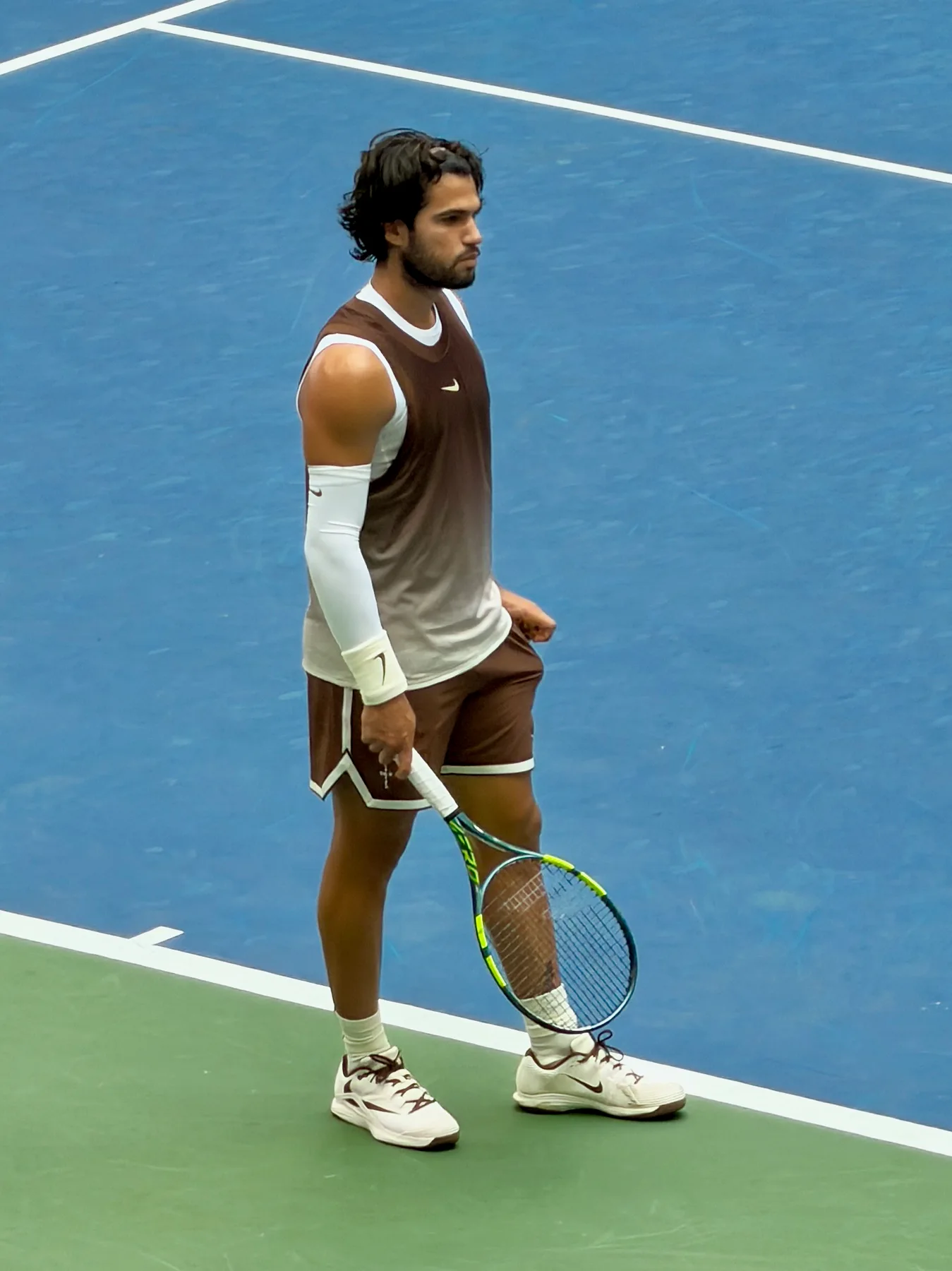Carlos Alcaraz walks on a blue hard court holding his racquet at the 2026 US Open