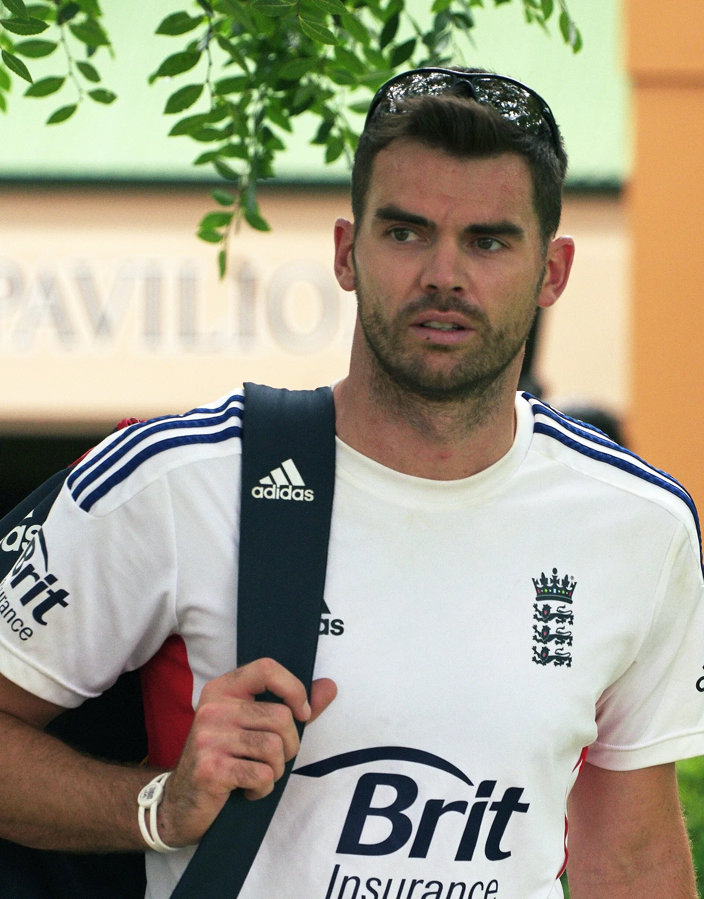 James Anderson in an England training shirt with a kit bag over his shoulder outside a pavilion