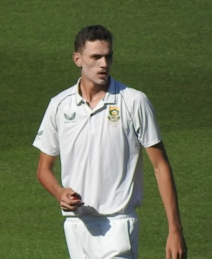 Marco Jansen in South Africa Test whites holding a red ball on the outfield