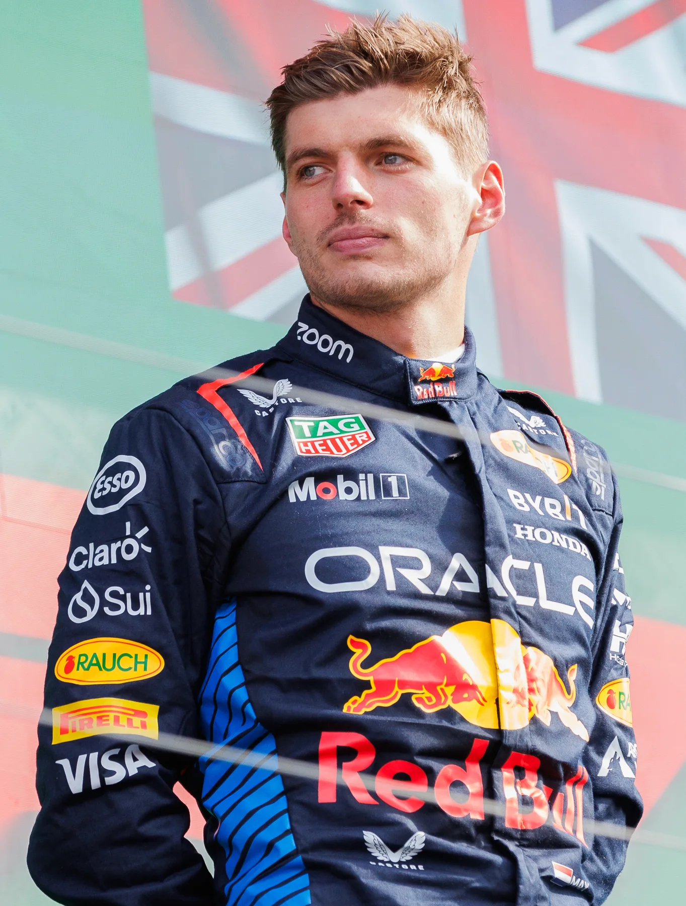 Max Verstappen in his Red Bull racing suit standing on a Formula 1 podium