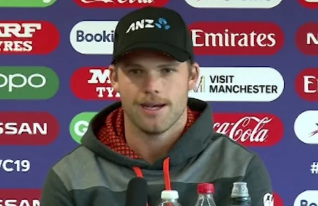 Lockie Ferguson in a black cap speaking at a New Zealand press conference in front of sponsor boards