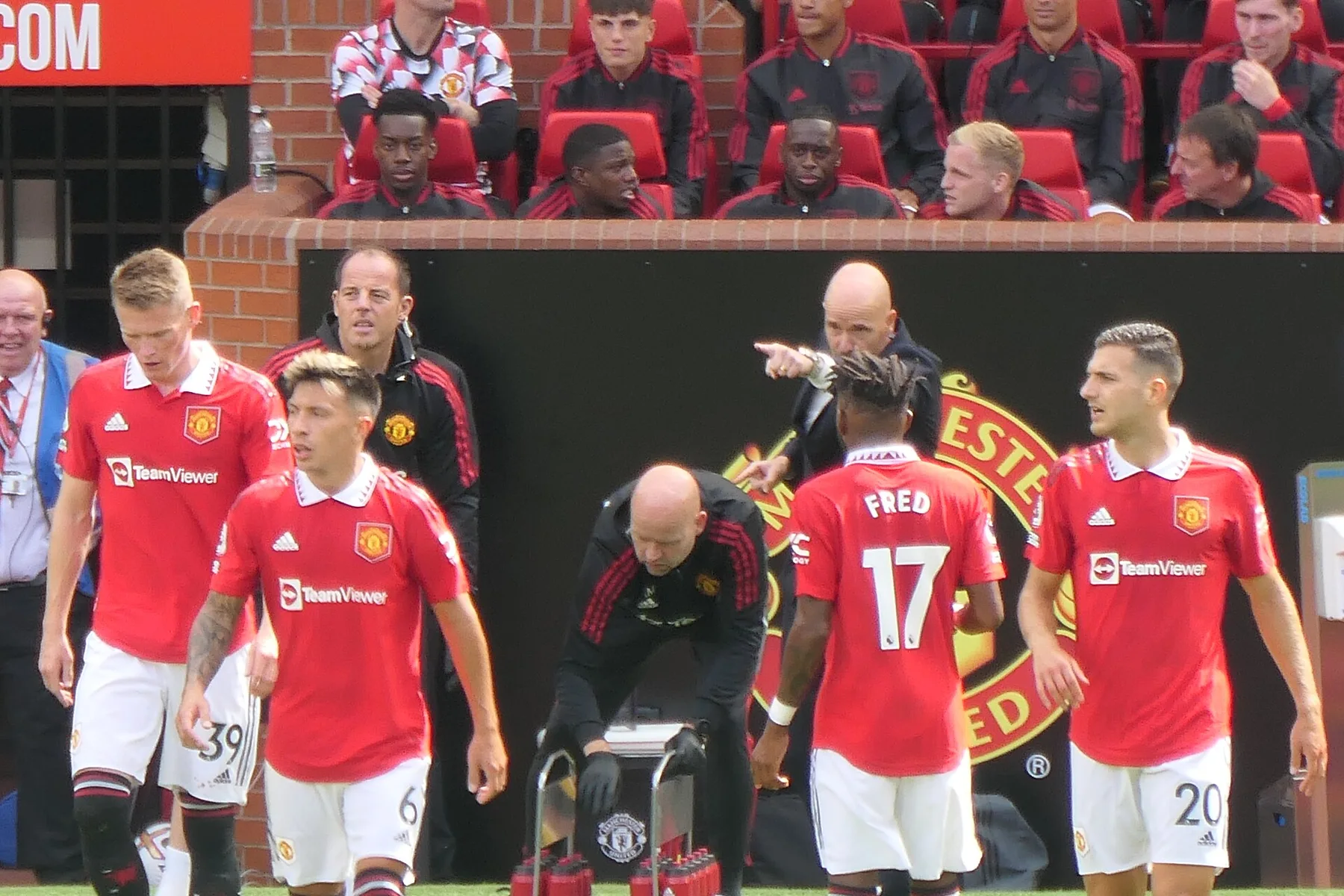 Erik ten Hag points from the Old Trafford touchline as Manchester United players in red wait on the pitch