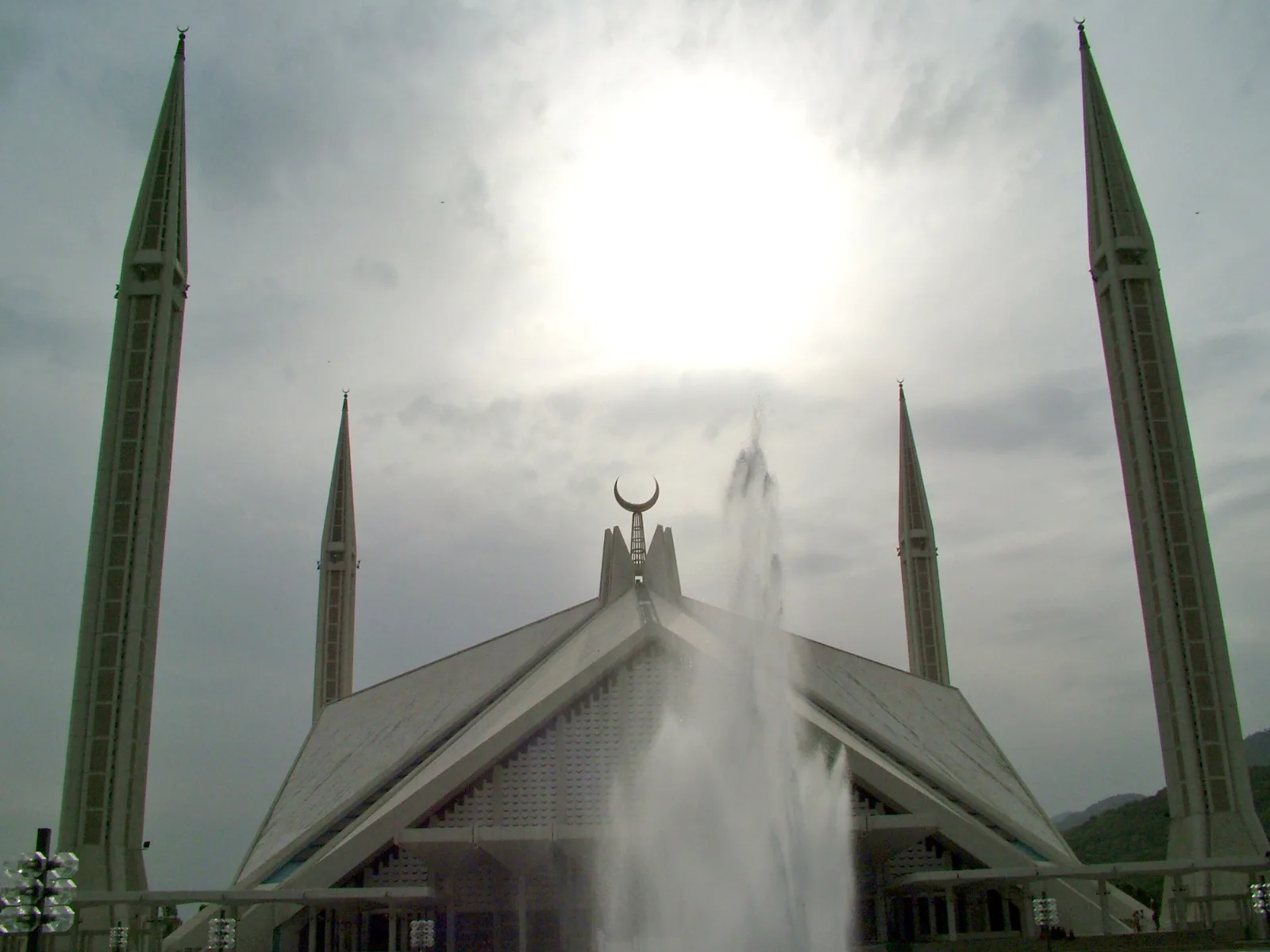 Faisal Mosque in Islamabad with its four minarets and a fountain in front under a cloudy sky