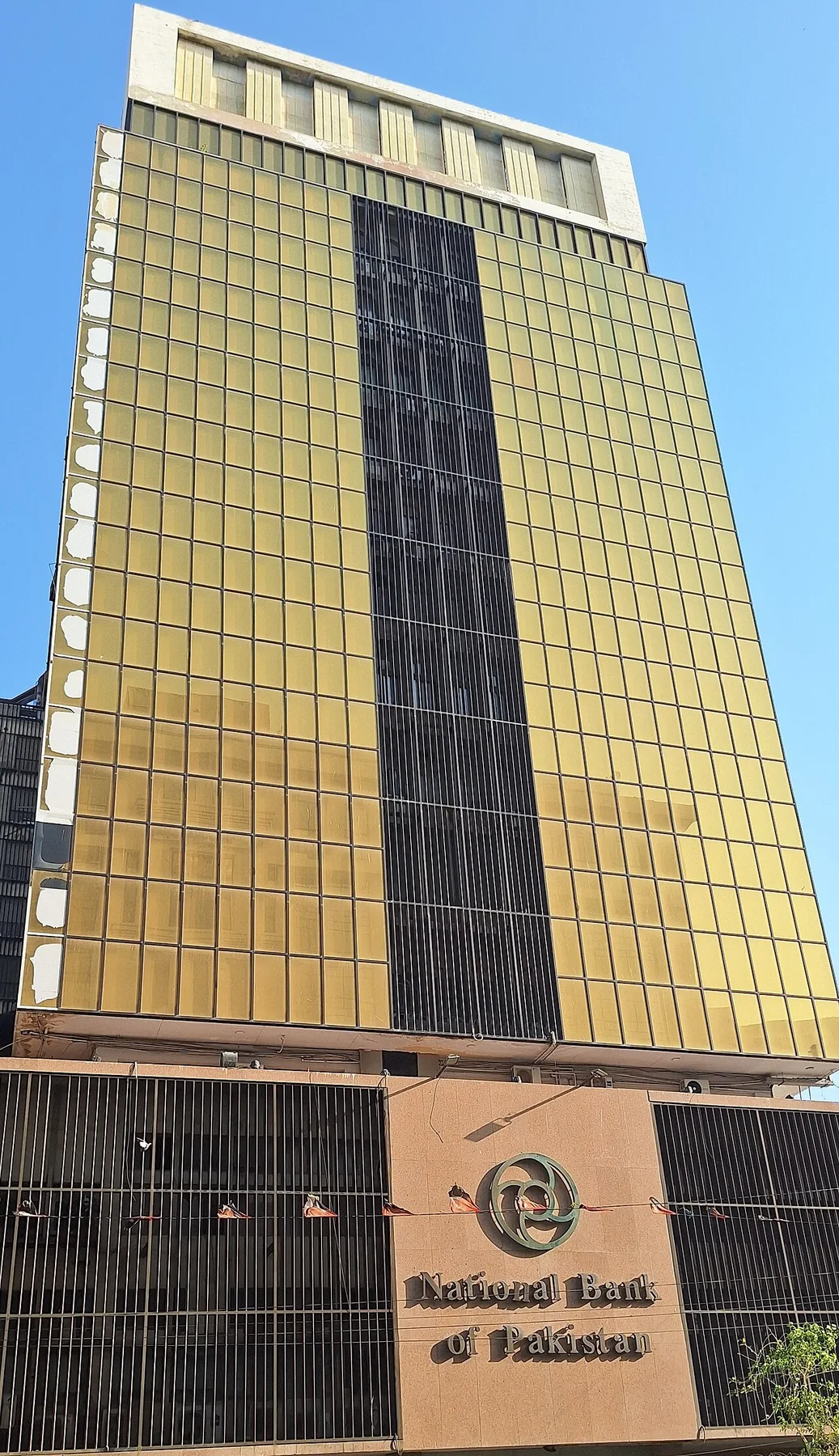 Gold-glass tower of the National Bank of Pakistan with the bank logo and name above the entrance