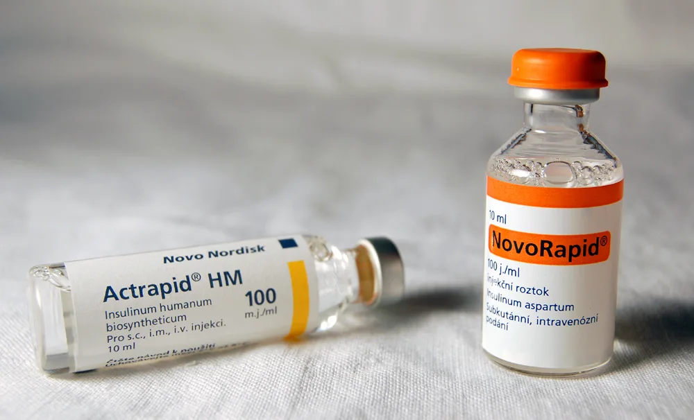Two insulin vials on a white cloth: Novo Nordisk Actrapid HM lying down and NovoRapid standing