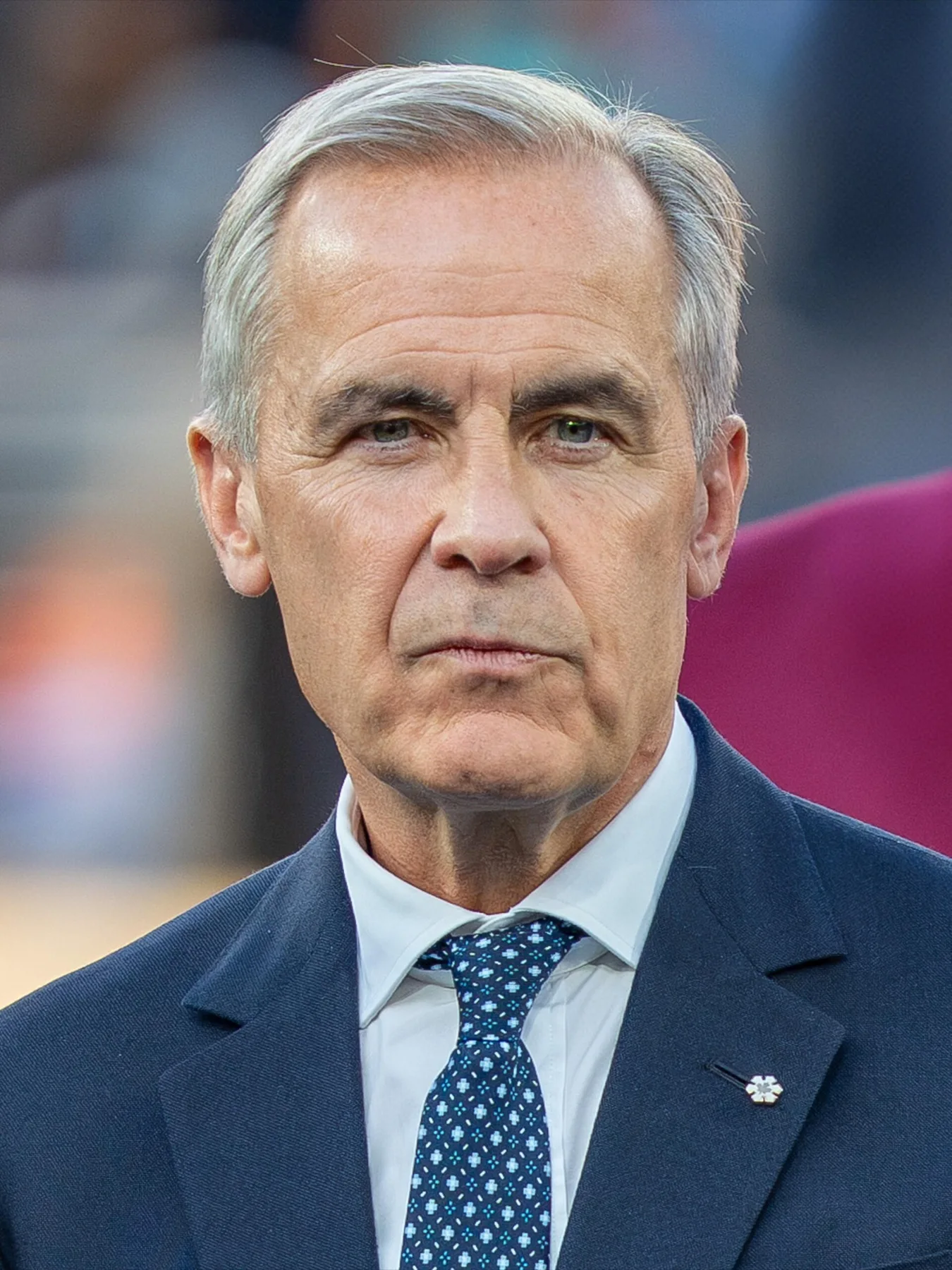 Canadian Prime Minister Mark Carney in a dark suit and blue tie at an outdoor event