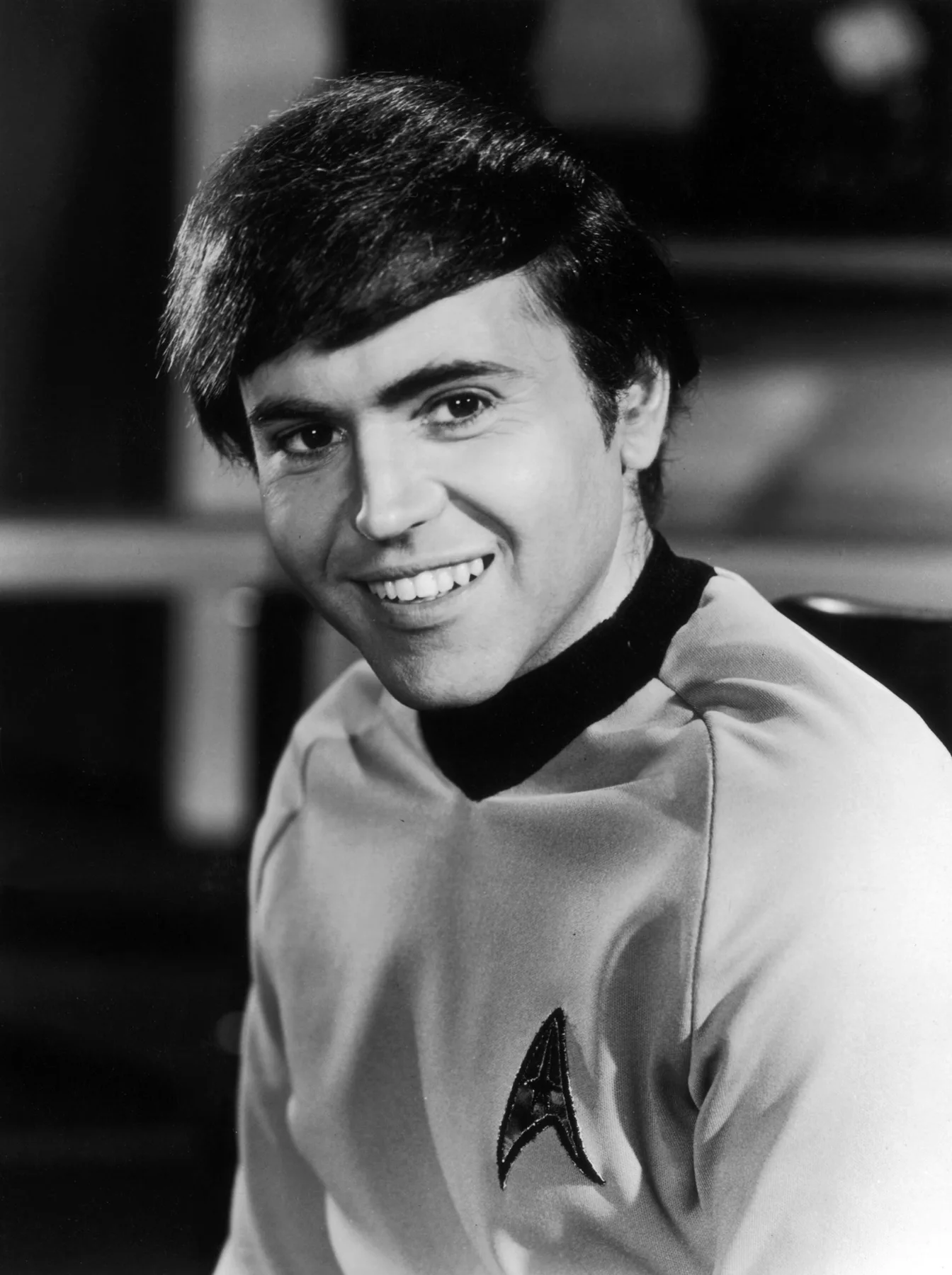 Walter Koenig smiling in a gold Starfleet uniform as Chekov, black-and-white Star Trek publicity portrait
