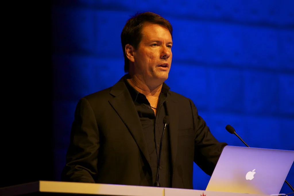 Michael Saylor speaking at a lectern with a laptop in front of a blue lit backdrop